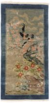 A Chinese rug, decorated with birds on branches, on a cream ground, 63cm x 120cm.