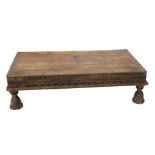 An Eastern hardwood table, the rectangular planked top with iron bolts or nails, above a carved frie