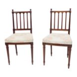 A pair of early 20thC mahogany bedroom chairs, each with a spindle turned back and padded seat, on t