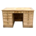 A late Victorian pine pedestal desk, top with moulded edge, above an arrangement of eleven drawers,