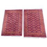 A pair of European cotton rugs in Eastern style, each with three rows of medallions, on a deep red g