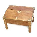 An Eastern hardwood and brass low writing table, the hinged sloped top enclosing a vacant interior,