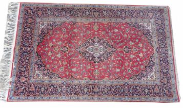 A Persian part silk Kashan rug, with a central medallion, in cream and navy, on a red ground with sp