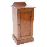 A late Victorian walnut bedside cabinet, the top with a raised back and moulded edge, above a panell