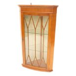 A yew bow fronted hanging corner cabinet, with a moulded cornice and single astragal glazed door enc