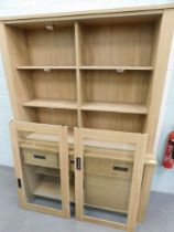 A beech finish display cabinet, with bookshelf and lighted top, above arrangement of three drawers a