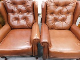 A pair of brown leatherette armchairs.