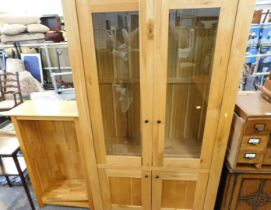 A beech effect display cabinet, with glazed doors and two cupboard base, and a matching bookcase. (2