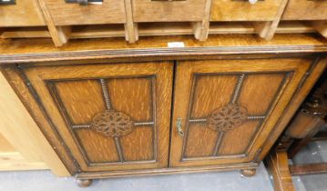 An oak two tier cupboard, with panelled and carved doors.