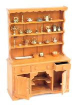 A doll's pine miniature Welsh dresser and decorations.