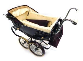 A vintage doll's pram, with a maroon body and cream leatherette livery.