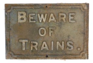 A cast metal sign, of rectangular form, bearing raised lettering 'Beware of trains', 55cm x 42cm.