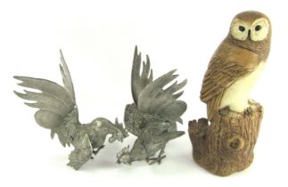 A 20thC resin model of an owl, mounted on tree stump, 29cm high, together with two cast metal fighti