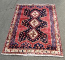 A Turkish red ground wool cut rug, with three central medallions within multiple borders, 234cm x 16