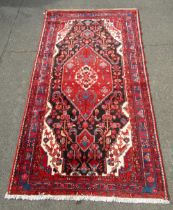 A Persian Hamadan red ground rug, of large central medallion surrounded by multiple borders, 310cm x