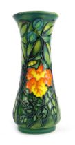 A Moorcroft pottery vase, of waisted form, decorated with flowers and leaves against a mottled green