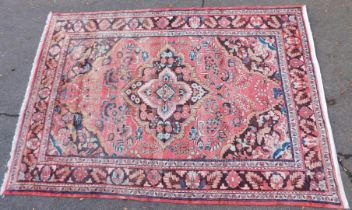 A Persian pink ground rug, with large central medallion against a floral ground, within multiple flo