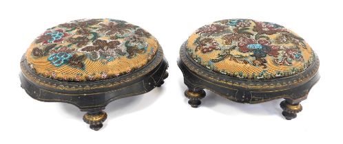 A pair of Victorian bead work footstools, the ebonised frames with gilt highlights, and floral decor