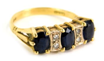 An 18ct gold sapphire and diamond gypsy ring, the panel set with three oval sapphires and inset with