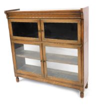 A 1920s oak sectional bookcase by Minty Limited of Oxford, with two glazed compartments, raised on l
