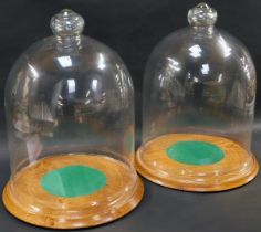 A pair of bell jar domes with turned oak stands, the stands made by J E Tolley of Spalding, 42cm hig