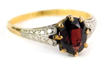 A dress ring, with central oval garnet, on V splayed white gold shoulders, on a yellow metal band, s