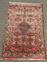 A Persian pink ground rug, with central medallion surrounded by further small medallion, within mult