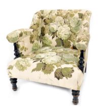 A Victorian ebonised low nursing chair, upholstered in floral fabric.