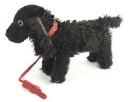 A mid century black dog soft toy, red leather collar and braided lead, 28cm high.