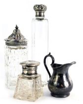 Three silver topped dressing table jars, comprising a bottle with floral cap, 17cm high, a silver ri