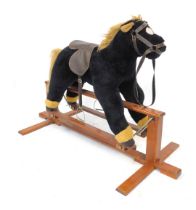 A child's plush rocking horse, on wooden framed stand.