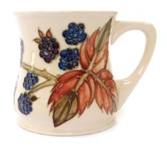 A Moorcroft pottery mug, decorated with brambles against a cream ground, impressed marks to undersid