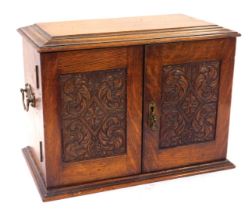 A 19thC oak smoker's cabinet, with carved panelled doors and a fitted interior with tobacco jar and