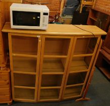 A beech finish concave front display cabinet, and a microwave.