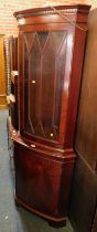 A walnut finish corner cabinet.