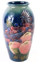 A William Moorcroft ovoid vase, on a blue ground, decorated with finches, fruits and berries, signed