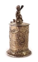 A 19thC continental silver metal miniature tankard, mounted with cherub, with embossed floral scroll