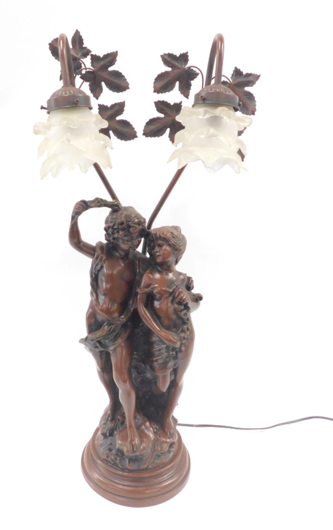 A bronzed resin table lamp, arched as two figures, with frosted glass shades, 76cm high.