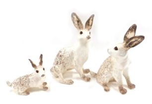 Three Winstanley hares, each on a white and brown ground, with Amber glass eyes, 26cm, 28cm, and 15c