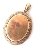 An Edwardian pinchbeck oval locket, with arched top and scroll outer border with a vacant shield, 13