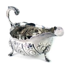 A Victorian silver sauce boat, with a fluted border acanthus leaf handle, embossed floral decoration