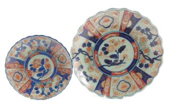 Two Imari style chargers, each on a blue ground with orange and blue floral detail and petalated bor