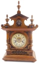 A late 19thC walnut cased mantel clock, with arched top with applied crest, on a white enamel dial w