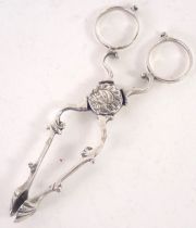 A pair of Victorian silver sugar tongs, with shell capped ends, and scroll arms with mounted face sp