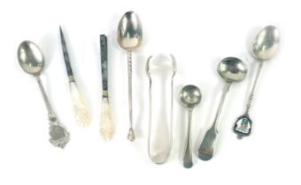 A group of white metal cutlery, comprising teaspoon, sugar tongs, souvenir spoons, etc., four stampe