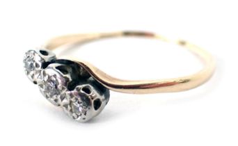 A three stone diamond twist ring, with three illusion set diamonds in white gold, on a yellow metal