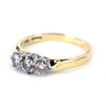 An 18ct gold three stone diamond dress ring, set with three round brilliant cut diamonds, the centra