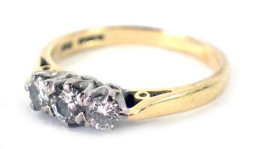 An 18ct gold three stone diamond dress ring, set with three round brilliant cut diamonds, the centra