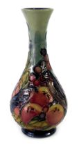 A William Moorcroft bud vase, on a blue ground, decorated with finches, fruits and berries, signed a