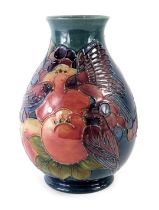 A William Moorcroft vase, on a blue ground, decorated with finches, fruits and berries, signed and s